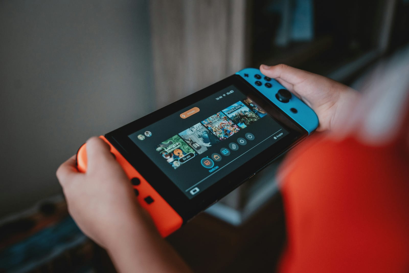 Criança segurando um Nintendo Switch com Joy-Con azul e vermelho, jogando